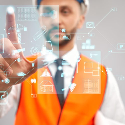 Close up of architect wearing reflective vest and helmet. Selective focus of digital tactile charts screen, man touching virtual icon on projection. Concept of digitalization, construction.